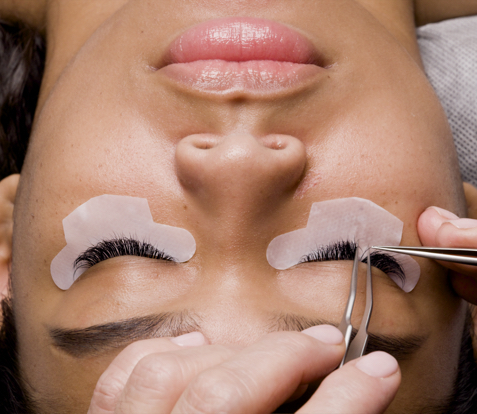 Applying eyelash extensions with precision tweezers on a client's closed eyes at Xtreme Lashes.